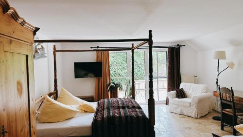 a bedroom with a four poster bed and a chair at Gästehaus Eschment in Bissersheim