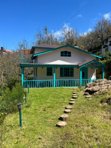 una casa con un camino delante de ella en Whispering Waters - Wild Rose Cottage, en Kodaikanal