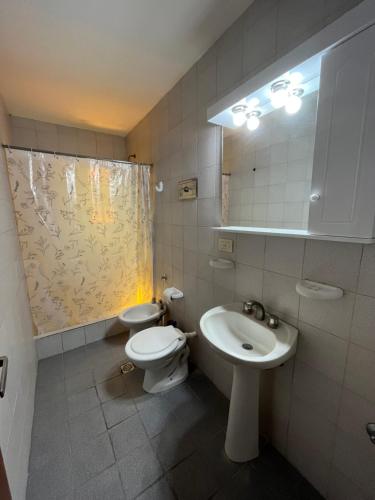 uma casa de banho com um WC, um lavatório e um espelho. em Duplex 2 - Rama Caida em Pinamar