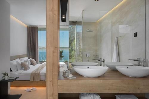uma grande casa de banho com 2 lavatórios e uma cama em Exclusive Villa Calma I - heated pool&spa sea view em Starigrad-Paklenica