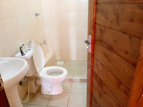 La salle de bains est pourvue de toilettes, d'un lavabo et d'une porte. dans l'établissement Tamara One Bedroom Apartment in Shanzu, à Mombasa