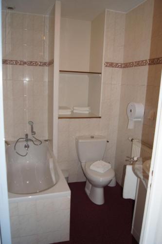 a bathroom with a toilet and a tub and a sink at Aux Trois Jean in Le Crotoy