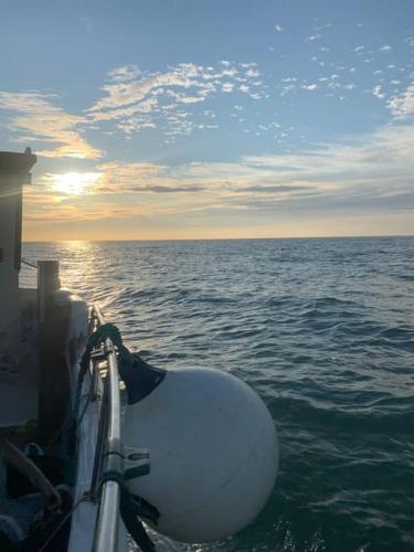 a boat in the ocean with the sun setting at Amber Lights Coastal Getaway, Greatstone in Greatstone