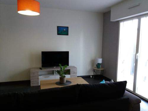 a living room with a black couch and a tv at Appartement au centre-ville Concarneau in Concarneau