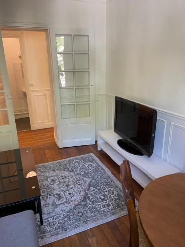 un salon avec une télévision à écran plat sur une étagère blanche dans l'établissement Magnifique appartement au centre de Montrouge, à Montrouge