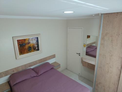 een slaapkamer met een paars bed en een schilderij aan de muur bij Uma agradável morada na praia para descansar ! in Governador Celso Ramos