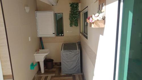 a small bathroom with a sink and a trash can at Uma agradável morada para descansar com a família ! in Governador Celso Ramos