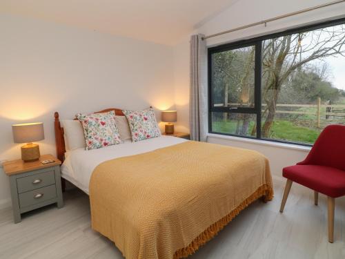 um quarto com uma cama, uma janela e uma cadeira vermelha em The Cook House em Devizes