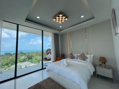 a bedroom with a white bed and a large window at Villa Savoy Sharm Samui in Chaweng Noi Beach