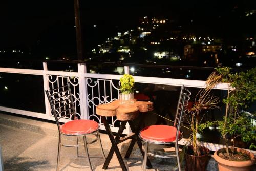 ein Tisch und zwei Stühle auf einem Balkon in der Nacht in der Unterkunft Plaza HomeStay in Masuri