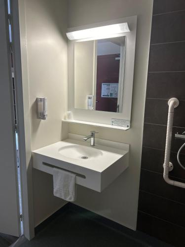 a bathroom with a white sink and a mirror at Hotel Wood Inn Bordeaux Aéroport in Mérignac