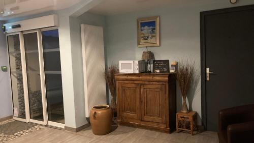 a kitchen with a microwave on top of a wooden cabinet at Aux Trois Jean in Le Crotoy