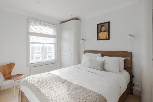 a white bedroom with a bed and a chair at Light-filled Primrose Hill Rooftop Retreat in London