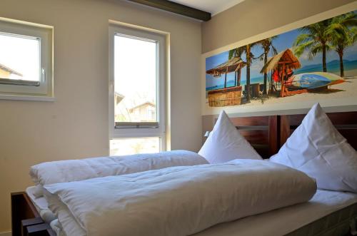 a bed in a bedroom with two windows at Typ A Ferienhaus - Kailua in Pelzerhaken
