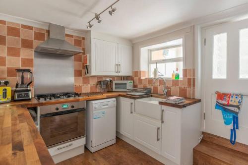 a kitchen with white cabinets and a stove top oven at Arnica Cottage in Wells next the Sea