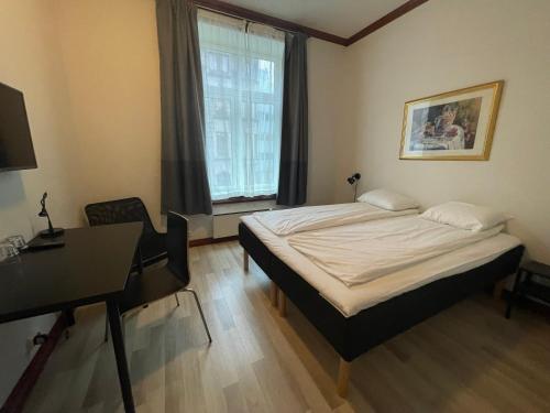 Schlafzimmer mit einem Bett, einem Schreibtisch und einem Fenster in der Unterkunft P-Hotels Oslo in Oslo