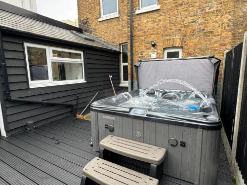 a hot tub on a deck next to a building at Herne Bay 2-Bedroom House with Private Hot Tub & Garden, Walk to Seafront in Kent