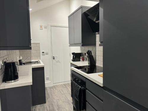 a kitchen with black cabinets and white counter tops at Herne Bay 2-Bedroom House with Private Hot Tub & Garden, Walk to Seafront in Kent