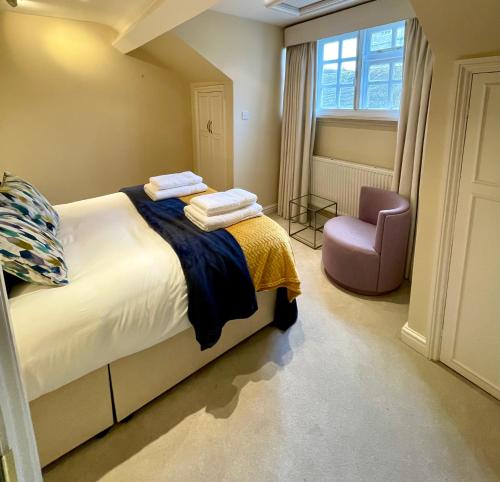 a bedroom with a bed and a chair and a window at Picturesque Thameside Apartment in Henley on Thames