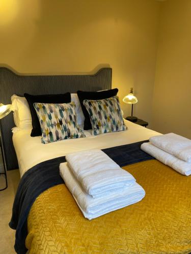 a bed with two pillows and towels on it at Picturesque Thameside Apartment in Henley on Thames
