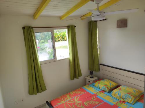 una camera con letto e finestra con tende verdi di Kaz a Roro a Sainte-Anne