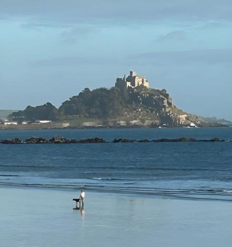 a man and a dog on a beach with a castle in the background at Ferney Croft in Saint Erth