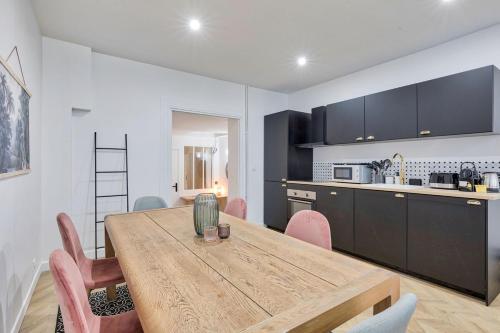 eine Küche und ein Esszimmer mit einem Holztisch und Stühlen in der Unterkunft Appartement luxueux proche Arc-de-Triomphe - 4P in Paris