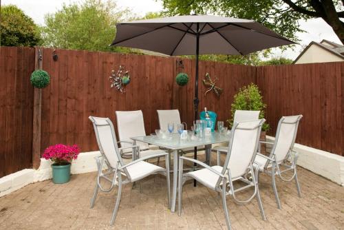 ein Tisch und Stühle mit einem Sonnenschirm auf einer Terrasse in der Unterkunft 4 Bed Luxury Family Home In The Heart Of Narberth in Pembrokeshire