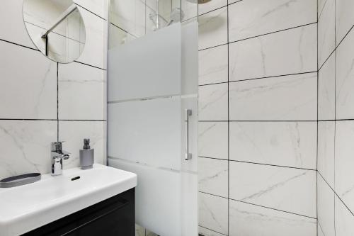een witte badkamer met een wastafel en een spiegel bij Appartement Suite 43 aux Portes de Paris in Aubervilliers