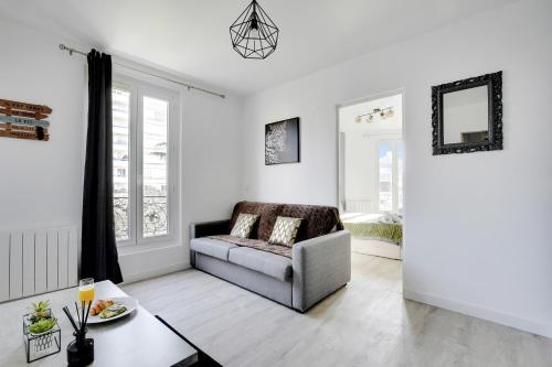 een woonkamer met een bank en een tafel bij Appartement Suite 43 aux Portes de Paris in Aubervilliers