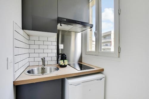 une petite cuisine avec un évier et une fenêtre dans l'établissement Appartement Suite 43 aux Portes de Paris, à Aubervilliers