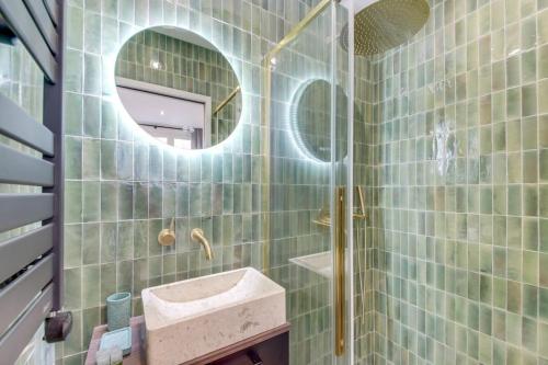 a green tiled bathroom with a sink and a mirror at Luxueuse maisonnette au coeur de Batignolles 17eme in Paris