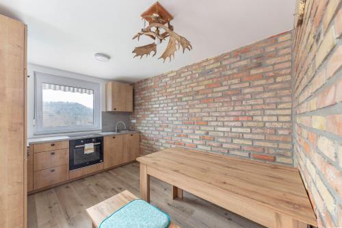 a kitchen with a brick wall and a wooden table at Apartma Naravni biser in Brezje