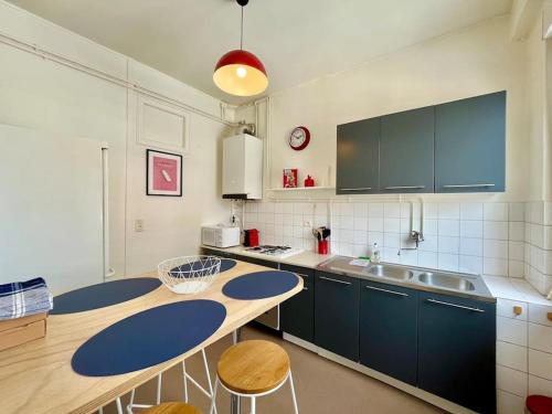 une cuisine avec des armoires bleues et une table et des chaises dans l'établissement Suite Montoison Reims, à Reims