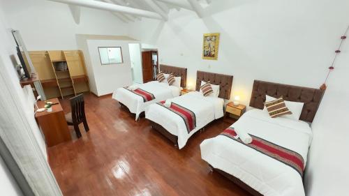 Habitación con 3 camas, mesa y sillas en Casona Libertrek Inn, en Cusco
