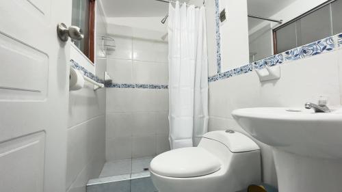 Un baño blanco con inodoro y lavabo. en Casona Libertrek Inn, en Cusco