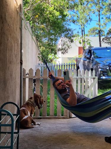a man laying in a hammock with a book and a dog at La casa de la Gaviota in Siguatepeque