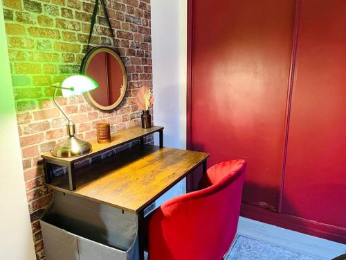d'un bureau avec une chaise rouge à côté d'un mur en briques. dans l'établissement La Suite Shelby, T3 hypercentre, à Beauvais