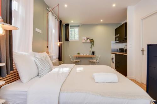 Cette petite chambre comprend un grand lit blanc et une table. dans l'établissement Lille train station: equipped studio, à Lille