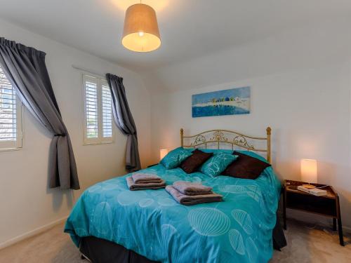 een slaapkamer met een blauw bed en handdoeken bij 3 Bed in Corfe Castle 78831 in Corfe Castle