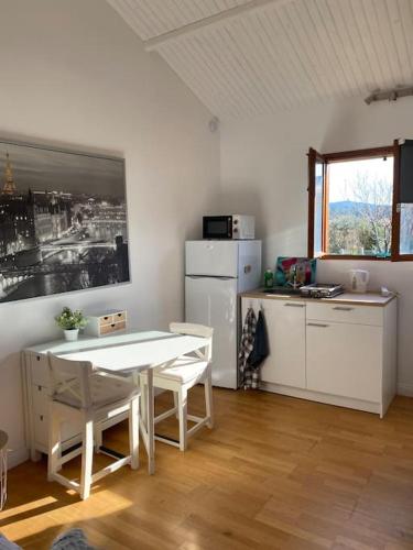 een keuken met een witte tafel en een witte koelkast bij Le Chalet Pignantais in Pignans