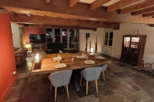 - une grande table et des chaises en bois dans le salon dans l'établissement ferme de caractère avec piscine et cheminée, à Sainghin-en-Mélantois