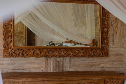 a mirror on a wooden frame on a wall at Billys Ayodya Villa in Perean