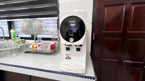 a white soap dispenser on a kitchen counter next to a door at Homestay Cikgu Sayang in Melaka