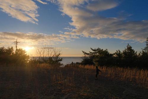 a person flying a kite on the beach at sunset at ワタリグラスハウス in Gamō