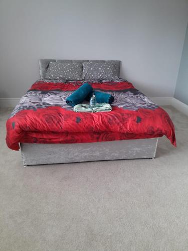 uma cama com um cobertor vermelho e almofadas azuis em Luxurious New Build em Nottingham