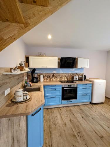 a kitchen with blue cabinets and a wooden floor at Landlust in Leutersdorf