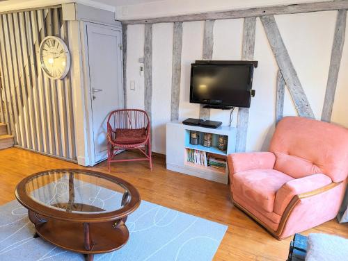 un salon avec une chaise et une télévision dans l'établissement La bi-coque du Courtgain, charmante et atypique, à Saint-Valery-sur-Somme