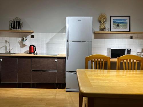 a kitchen with a refrigerator and a table with chairs at Rest Easy Inn in Ulaanbaatar