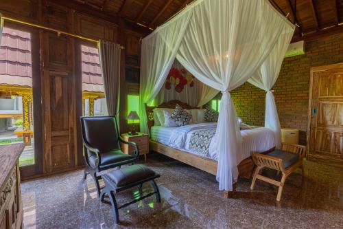 a bedroom with a canopy bed and two chairs at Billys Ayodya Villa in Perean